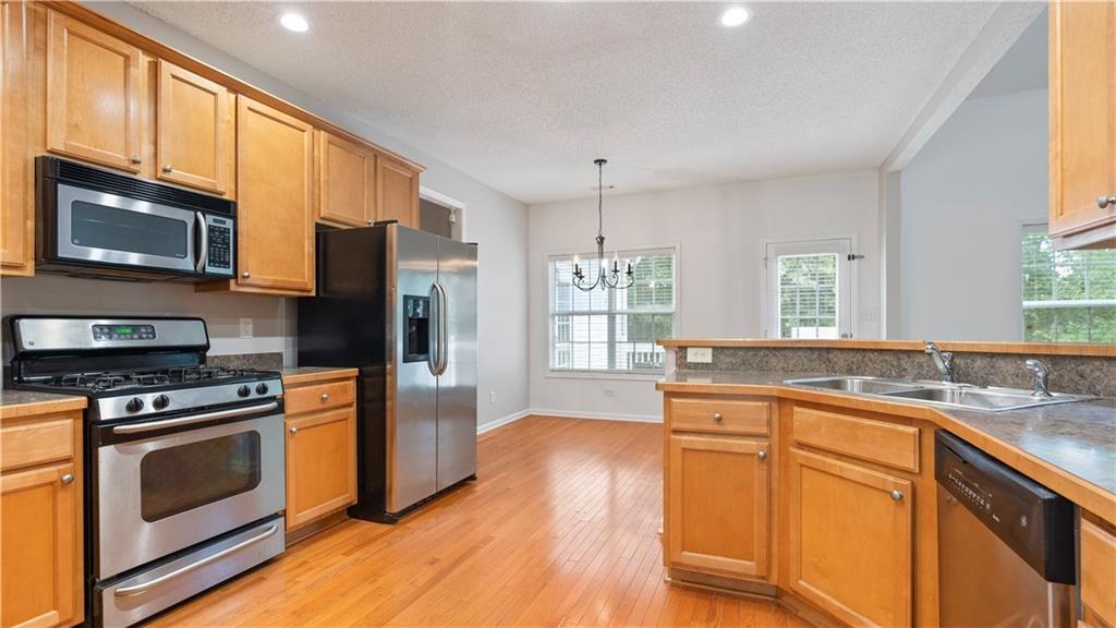 91 Medallion Park Newnan, GA 30265 - Photo 13 of 45 a kitchen with stainless steel appliances granite countertop a stove a sink dishwasher a refrigerator and a microwave oven with wooden floor