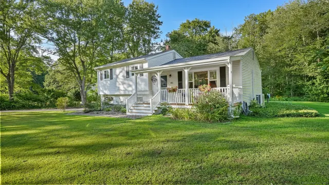 a view of a house with a big yard and large trees