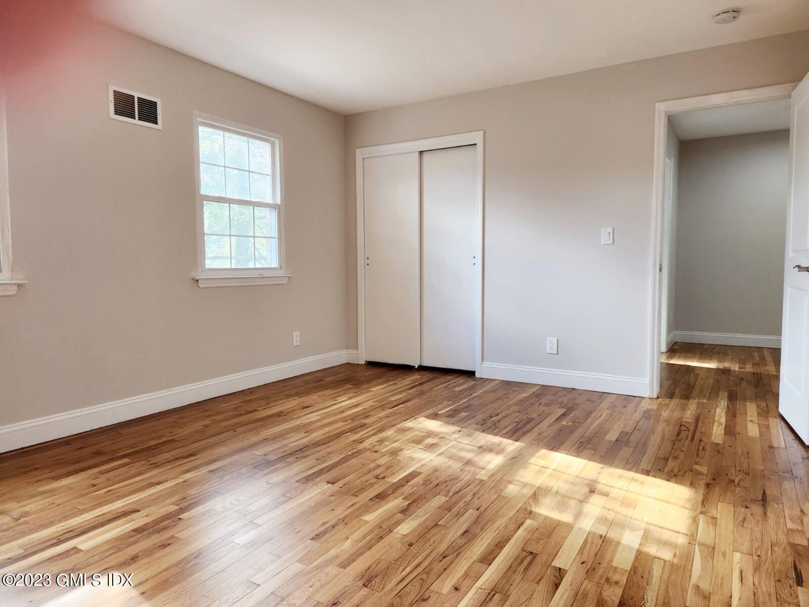 96 Valley Road, Unit 18 Cos Cob, CT 06807 - Photo 17 of 24 a view of an empty room and window and wooden floor