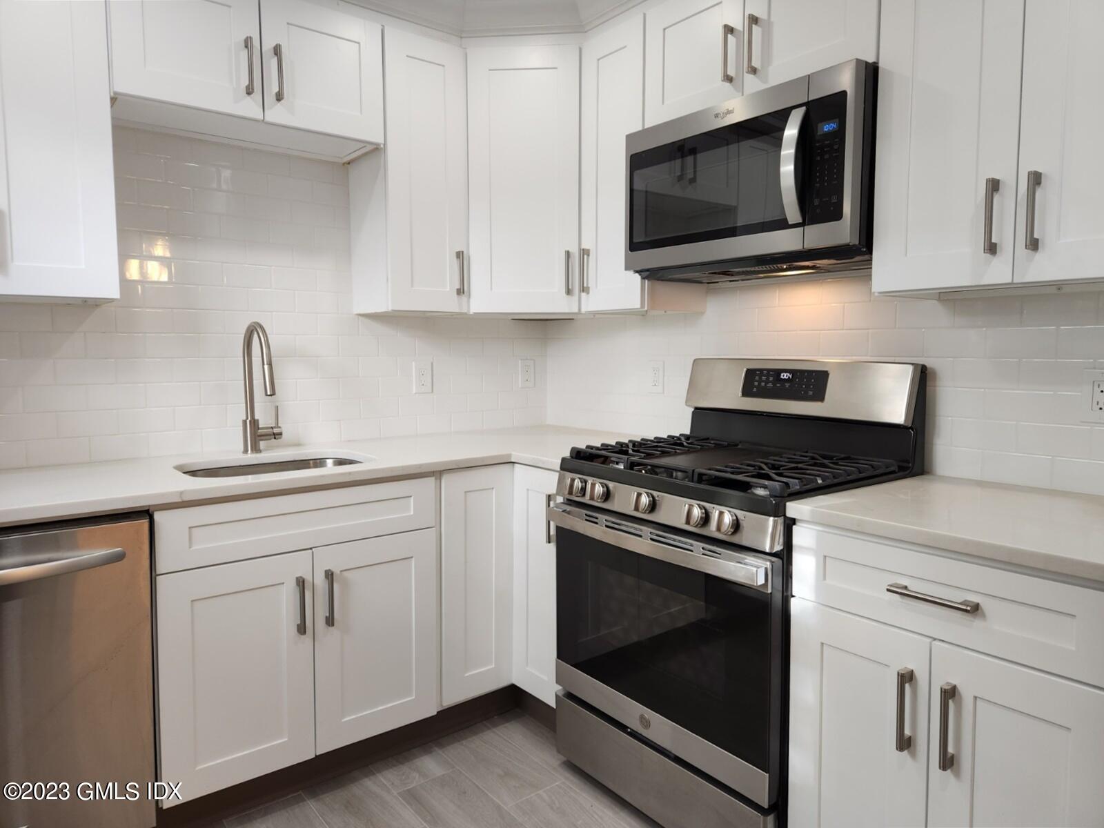 96 Valley Road, Unit 18 Cos Cob, CT 06807 - Photo 5 of 24 a kitchen with white cabinets and stainless steel appliances