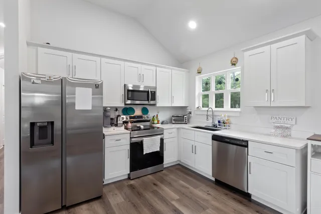 a kitchen with cabinets stainless steel appliances a sink and a window