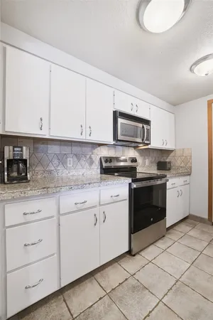 a kitchen with granite countertop white cabinets and stainless steel appliances