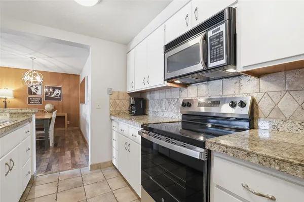 a kitchen with stainless steel appliances granite countertop a stove microwave and cabinets