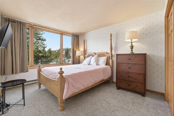 a spacious bedroom with a bed and a dresser next to a window