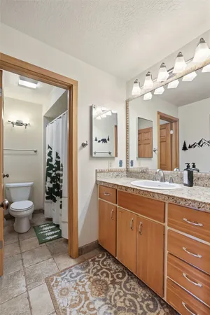 a bathroom with a granite countertop sink mirror and a toilet
