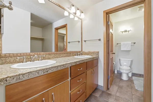 a bathroom with a granite countertop sink a mirror and a toilet