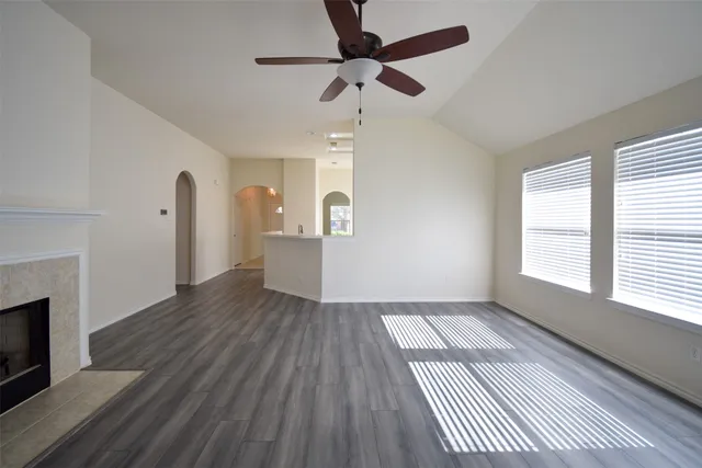 a view of an empty room with wooden floor fireplace and a window
