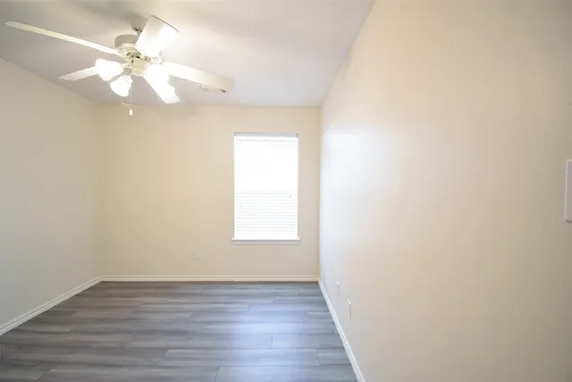 an empty room with wooden floor fan and window