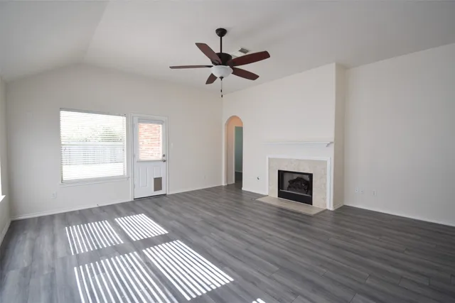 an empty room with wooden floor a fireplace and windows