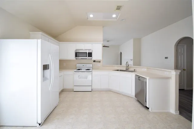 a kitchen with white cabinets and white appliances
