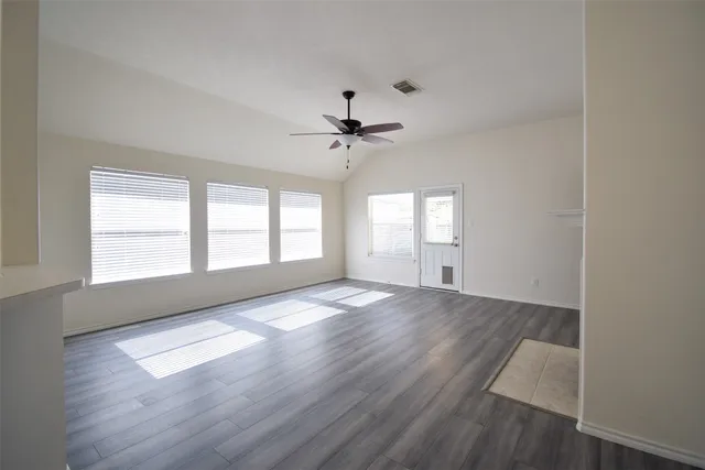 an empty room with wooden floor and windows
