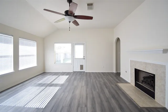 a view of an empty room with wooden floor fireplace and a window