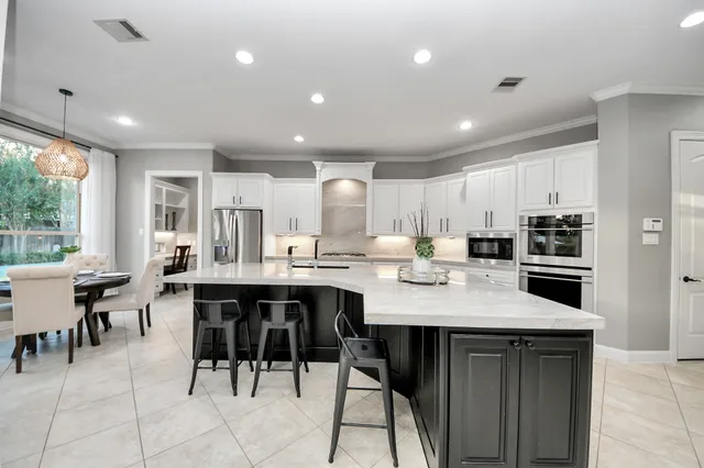 a large kitchen with kitchen island a sink a stove a dining table and chairs