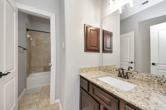 a bathroom with a granite countertop sink shower and a mirror