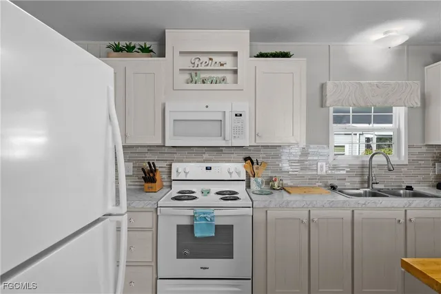 a kitchen with a white stove refrigerator and white cabinets with wooden floor