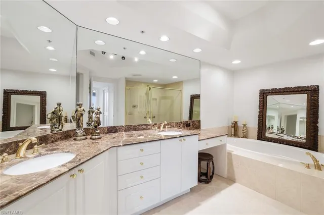 a bathroom with a sink double vanity granite tub shower and a mirror