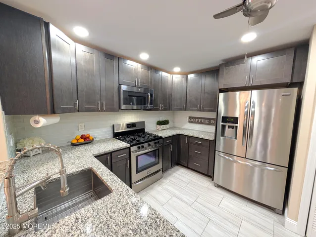 a kitchen with stainless steel appliances granite countertop a refrigerator stove and sink