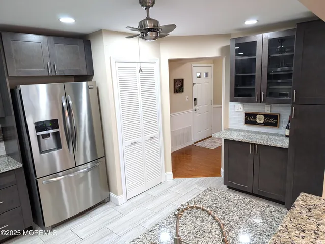 a kitchen with stainless steel appliances granite countertop a refrigerator a stove and a sink with wooden floor