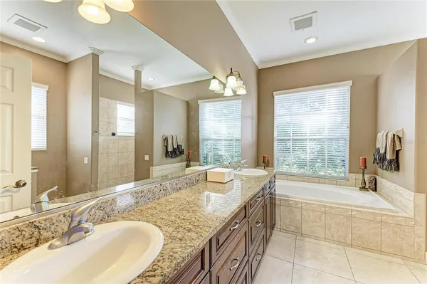 a bathroom with a granite countertop double vanity sink a mirror and a shower