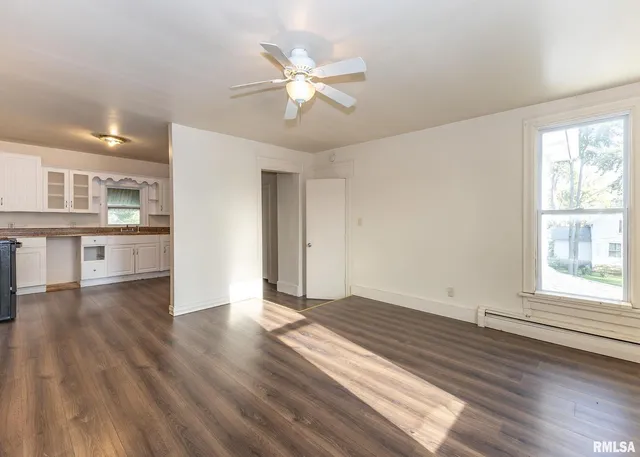 an empty room with wooden floor fan and windows