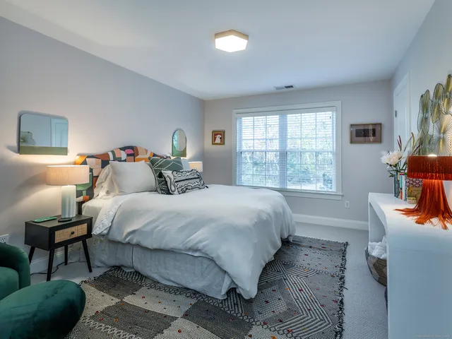 a bedroom with a bed a large window and book self