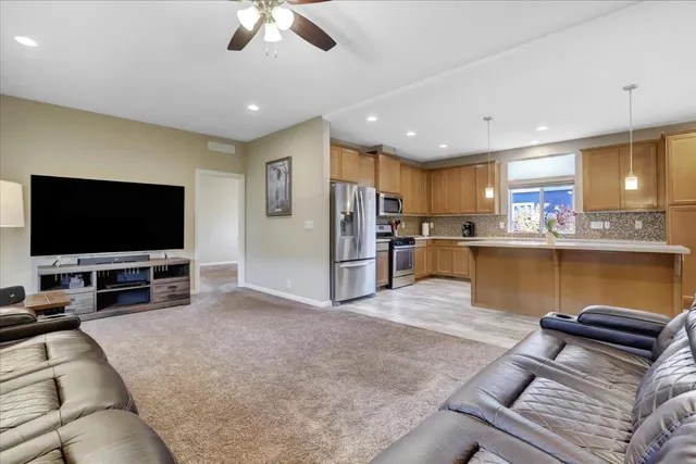 a living room with stainless steel appliances furniture and a flat screen tv