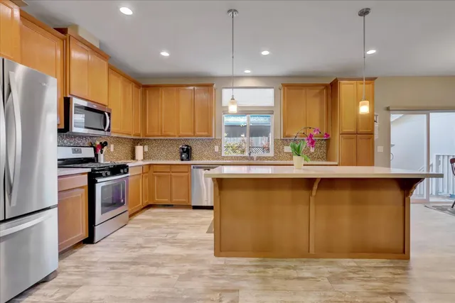 a kitchen with stainless steel appliances granite countertop a sink a stove a refrigerator cabinets and a kitchen island