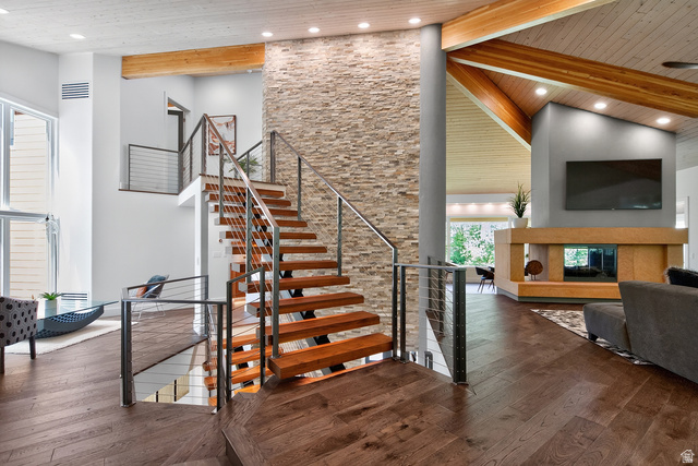 11454 South Oberland Road Sandy, UT 84092 - Photo 6 of 103 Hardwood flooring throughout, a modern floating staircase with cable railings, a stone accent wall, and an open-concept living area with a fireplace