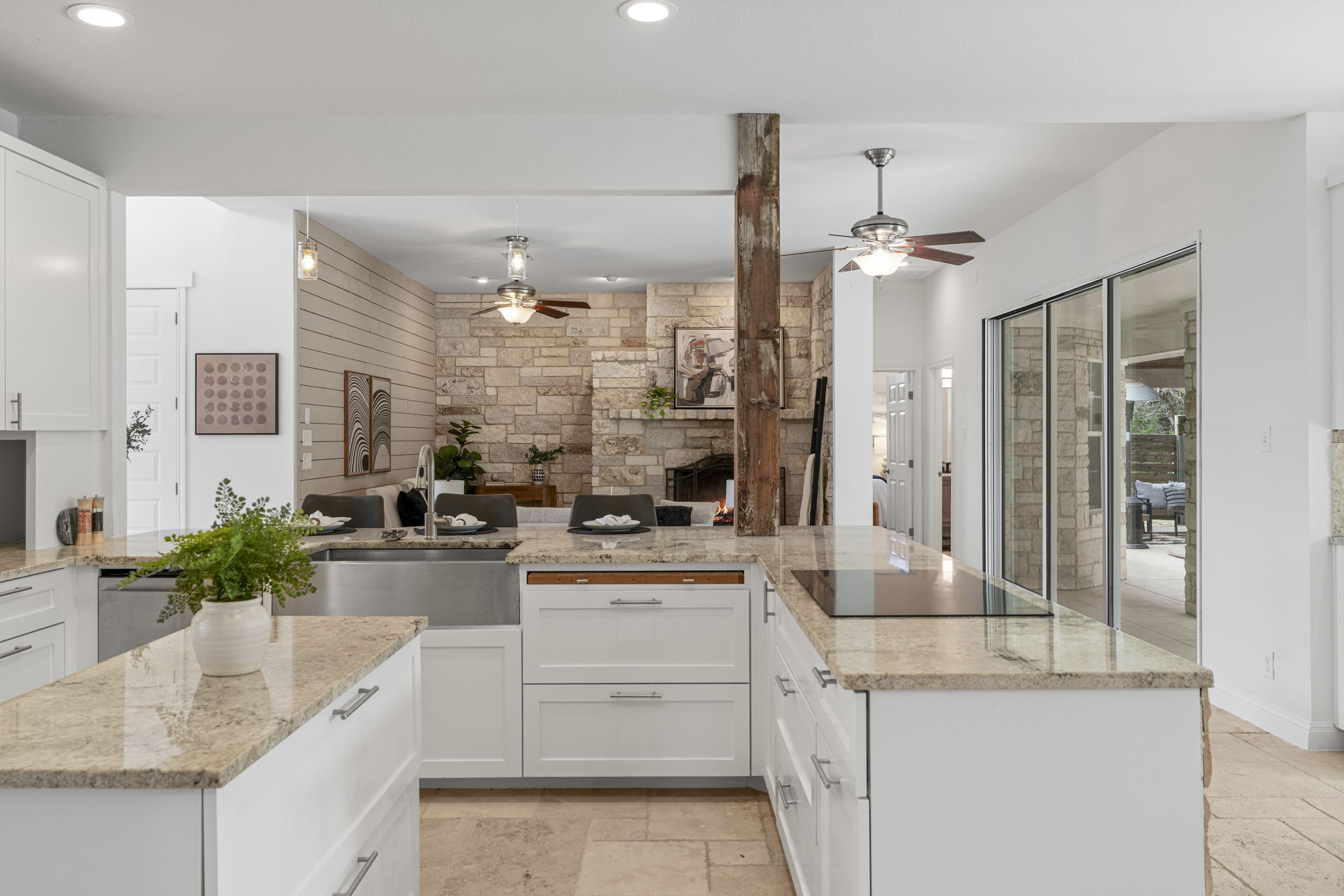 1129 Cedar Pass Road Driftwood, TX 78619 - Photo 13 of 40 This is probably the best view of the entire house because it shows you exactly how the home "lives." Standing here at the U-shaped kitchen island, you are literally at the center of everything. Whether you're prepping a meal or just cleaning up, you have a perfect line of sight to the fireplace, the shiplap accent wall, and those gorgeous backyard views through the sliders.