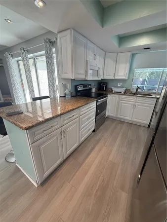 a kitchen with stainless steel appliances granite countertop a refrigerator a stove a sink dishwasher and a refrigerator with wooden floor