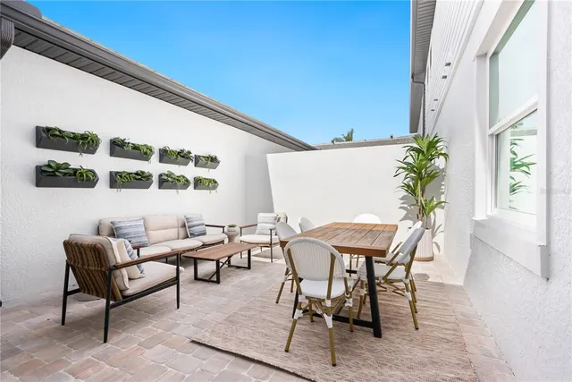 a patio with table and chairs and potted plants