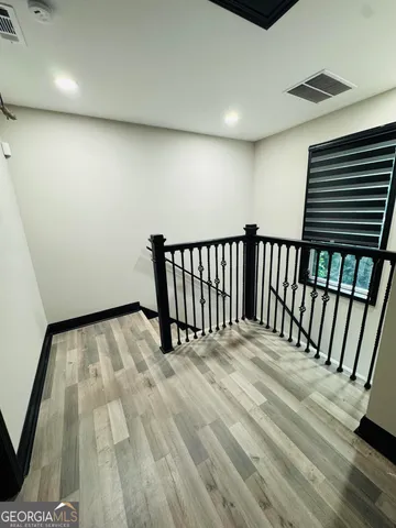 an empty room with wooden floor fan and windows