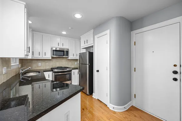 a kitchen with kitchen island granite countertop stainless steel appliances a stove a refrigerator a sink a counter space and cabinets
