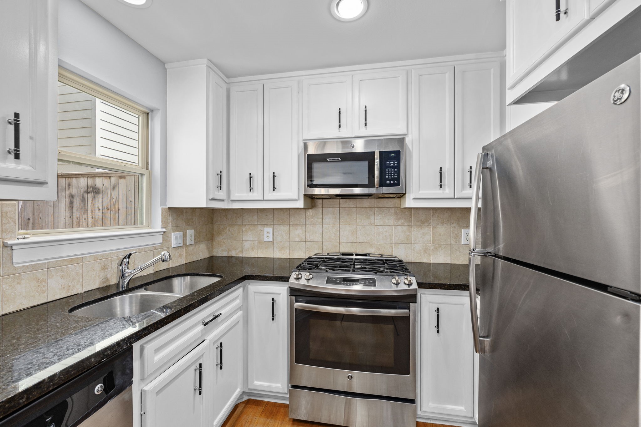5951 S Loop East, Unit 50 Houston, TX 77033 - Photo 10 of 23 a kitchen with stainless steel appliances granite countertop white cabinets a refrigerator a sink and a stove