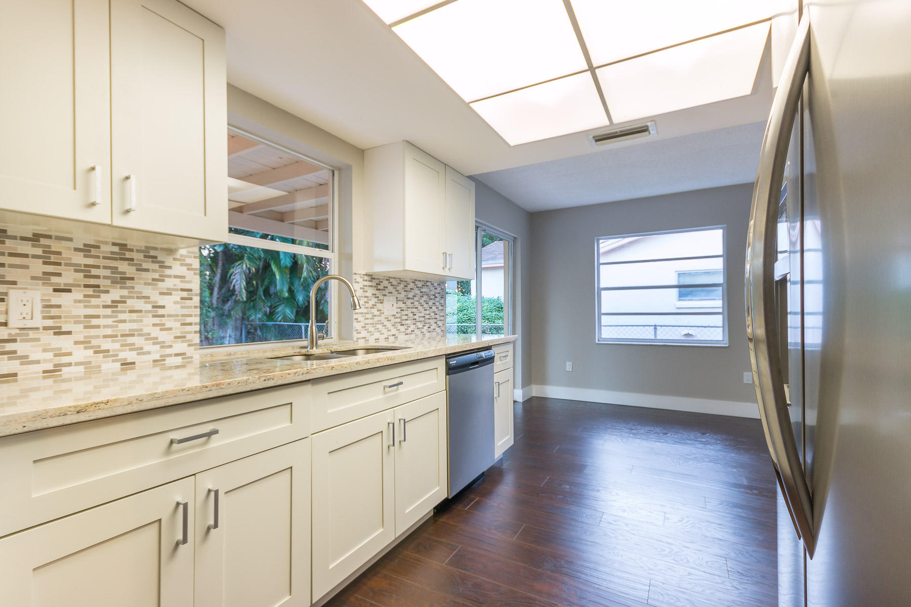 9222 Southwest 1st Place Boca Raton, FL 33428 - Photo 3 of 23 a kitchen with stainless steel appliances granite countertop a refrigerator a sink and wooden floors