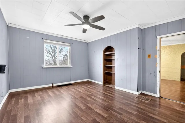 a empty room with wooden floor fan and window