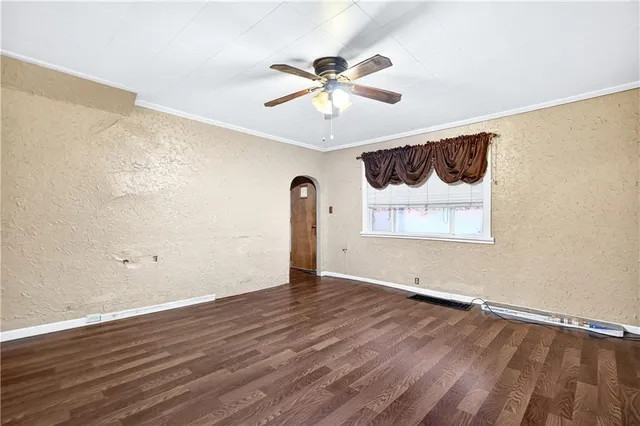 a view of an empty room with wooden floor and a ceiling fan