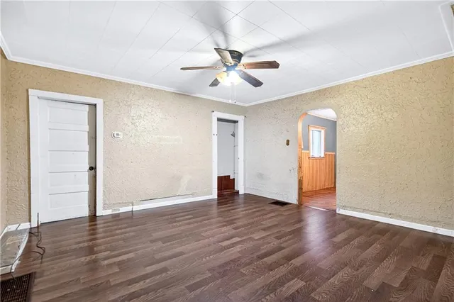 an empty room with wooden floor ceiling fan and windows