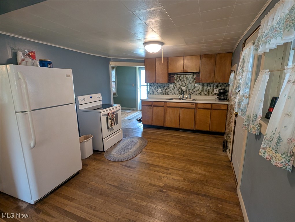 2356 Walter Main Road Geneva, OH 44041 - Photo 16 of 27 Kitchen with brown cabinets, a sink, white appliances, light countertops, and dark wood-type flooring