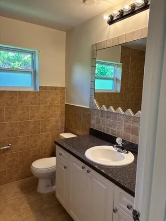 a bathroom with a granite countertop toilet a sink and mirror