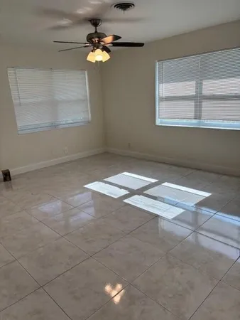 an empty room with windows and fan