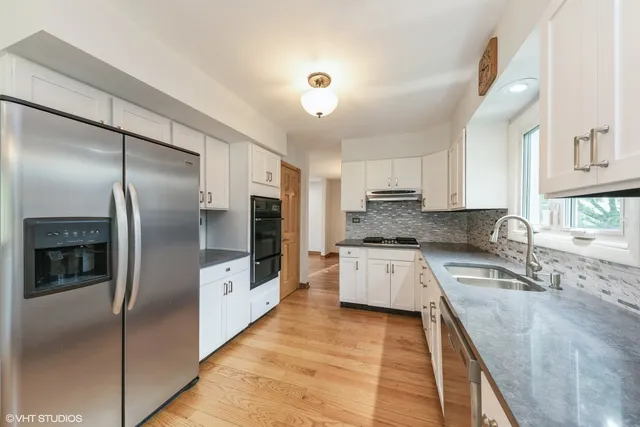 a kitchen with granite countertop a refrigerator a sink a stove and oven