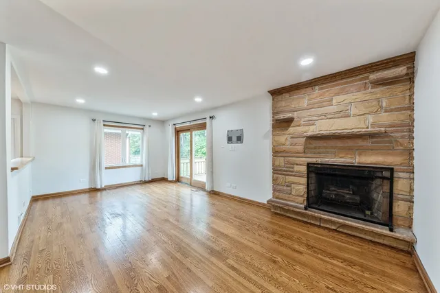 a view of an empty room with wooden floor fireplace and a window