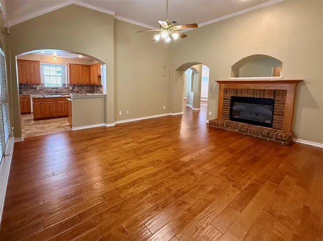 a view of an empty room with window and wooden floor