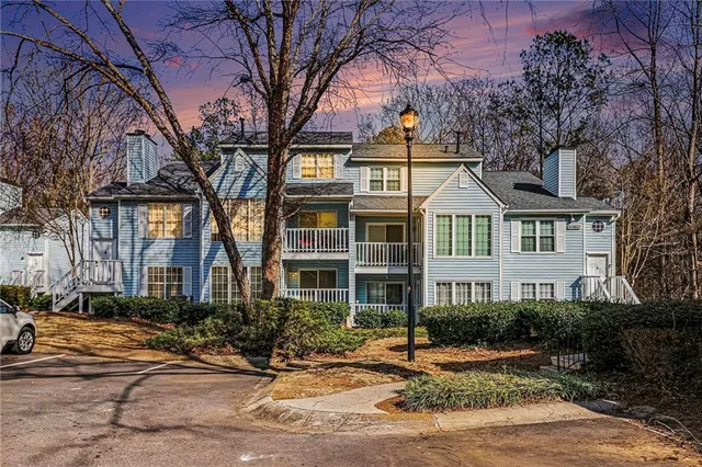 a view of a white house with large windows and a tree