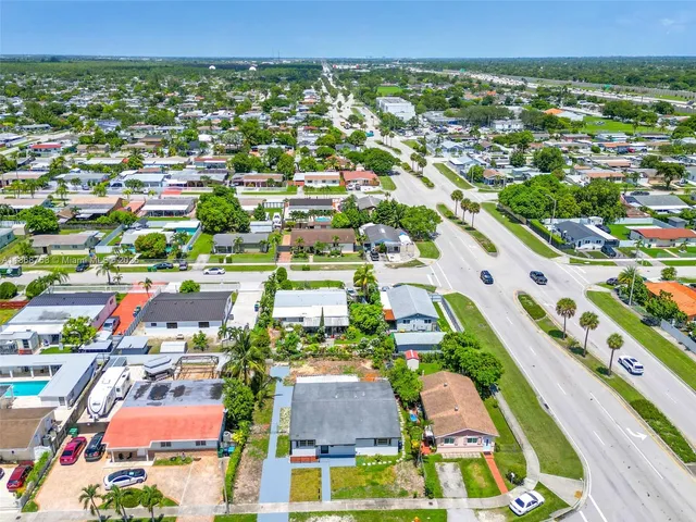 an aerial view of residential houses with outdoor space and trees
