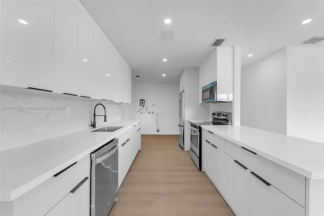 a large kitchen with stainless steel appliances lots of counter top space sink and cabinets