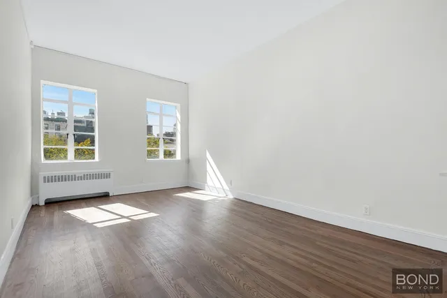 a view of empty room with wooden floor and window