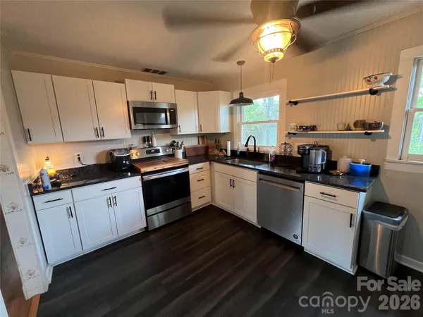 a kitchen with a sink dishwasher a stove a microwave oven and a dining table with wooden floor