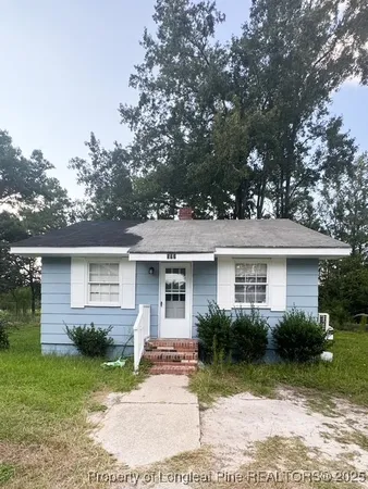 a front view of house with yard and trees around